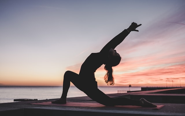 Person stretching in a lunge at sunset